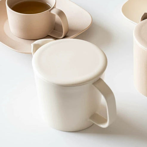Cream teapot on white background with other ceramic items