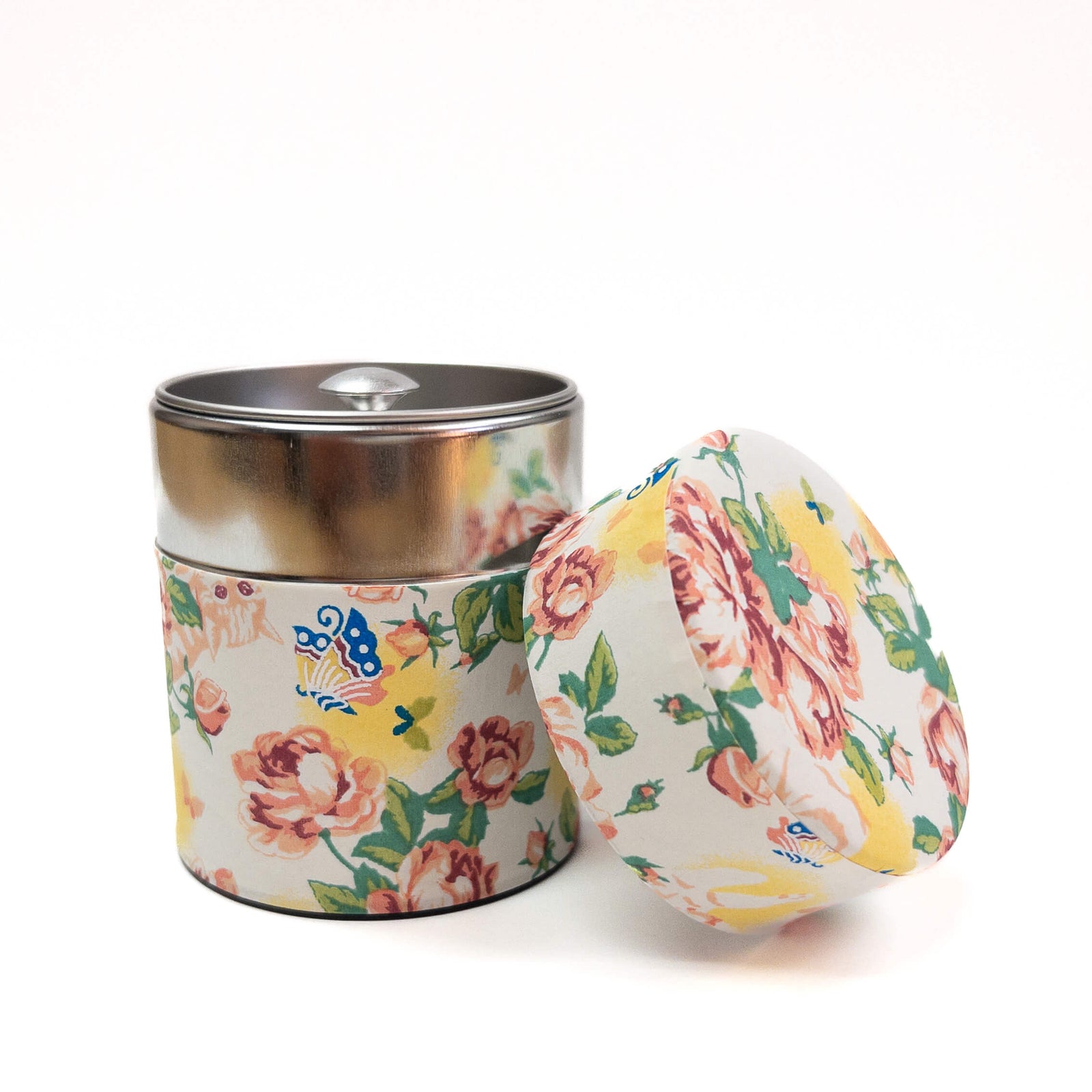 Floral-patterned metal tea canister with lid on a white background