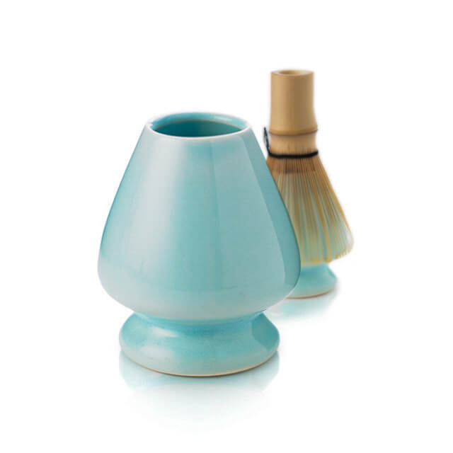 Light blue ceramic whisk holder with a bamboo whisk on a white background
