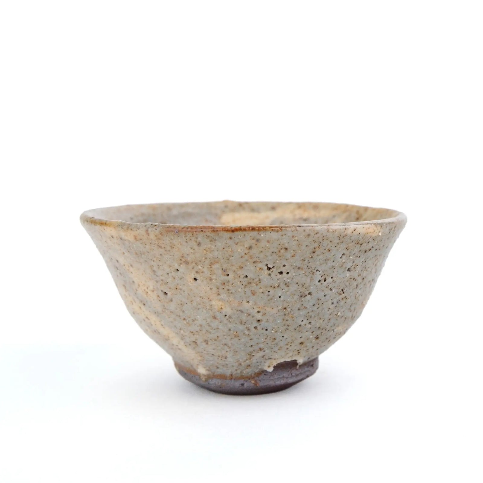 A handmade ceramic gong fu teacup with a textured, speckled glaze in earthy beige and brown tones, set against a plain white background.