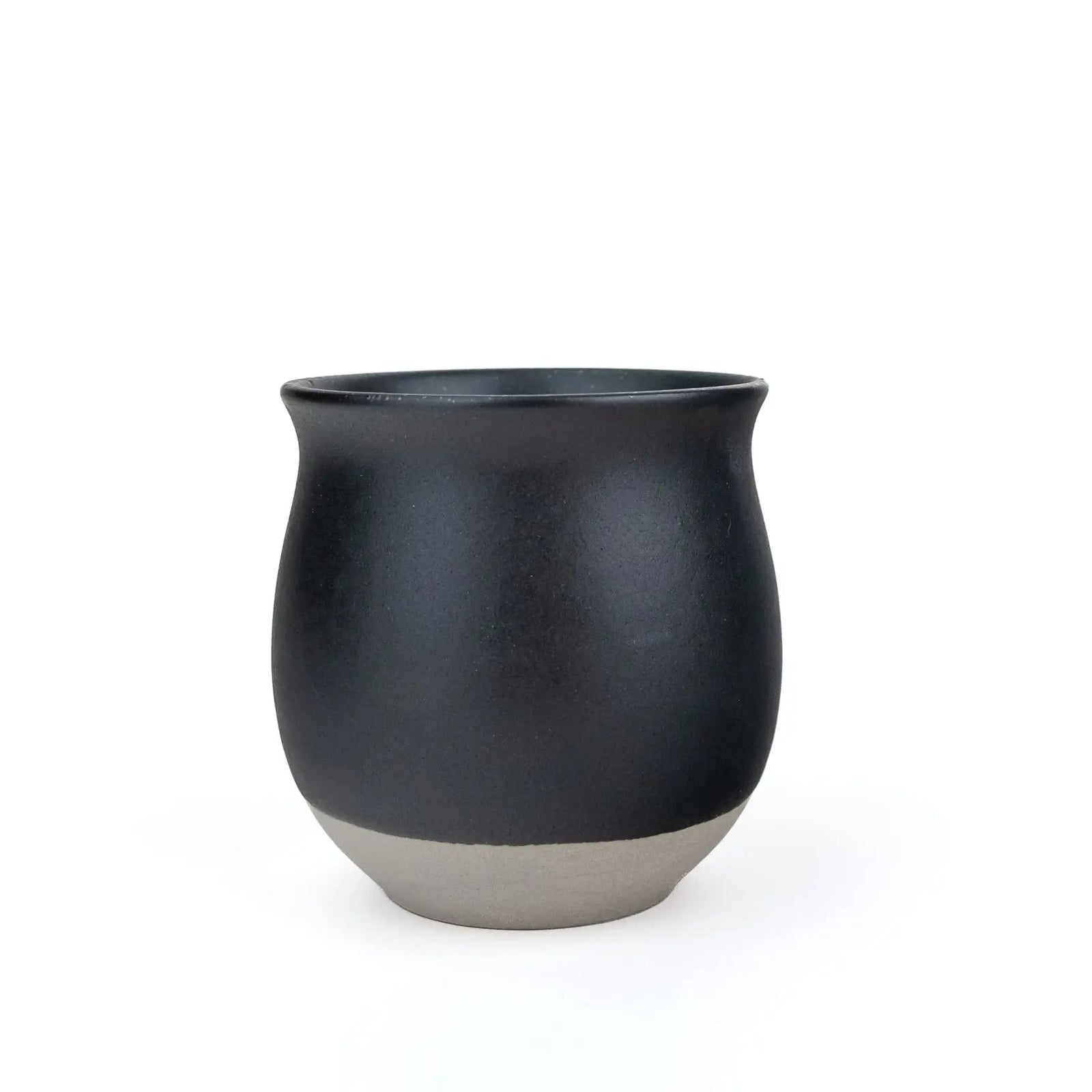 A matte black ceramic cup with a contrasting light gray textured base, photographed against a seamless white background.